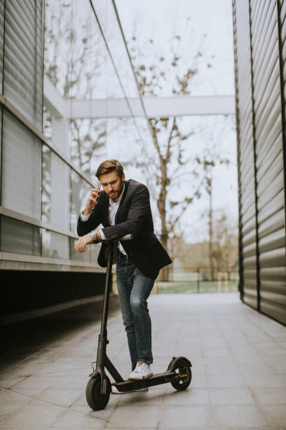 istock Young businessman using mobile phone  on electric scooter 1318625044