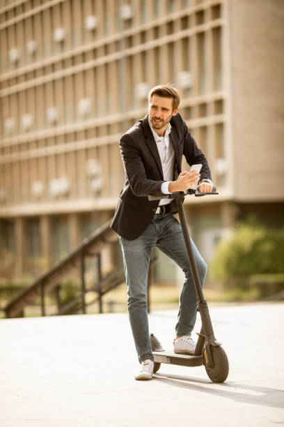 istock Young businessman using mobile phone  on electric scooter 1318625054