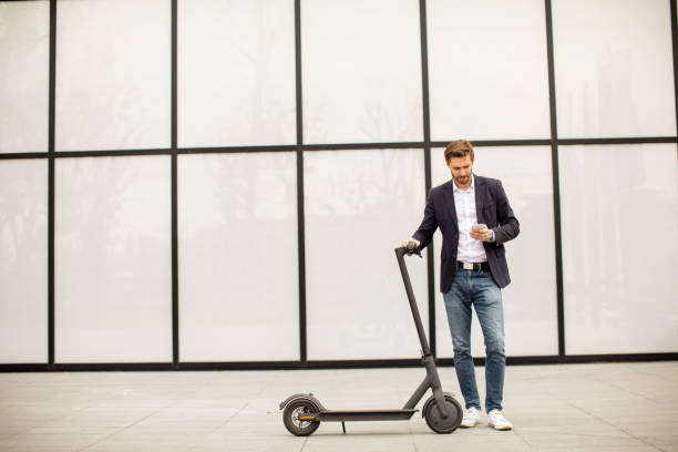 istock Young businessman using mobile phone  on electric scooter 1318625059