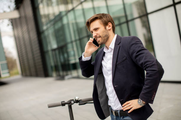 istock Young businessman using mobile phone  on electric scooter 1318625074