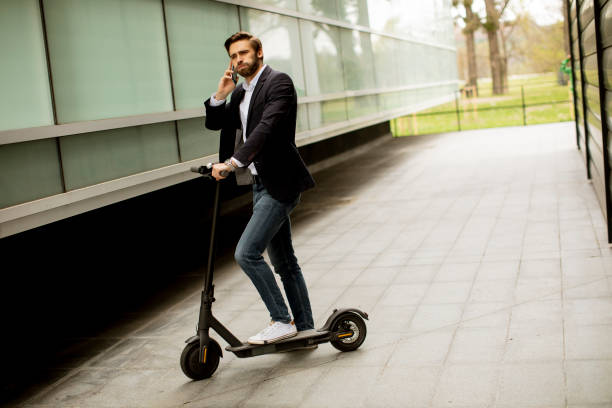 istock Young businessman using mobile phone  on electric scooter 1318625084