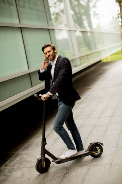 istock Young businessman using mobile phone  on electric scooter 1318625088