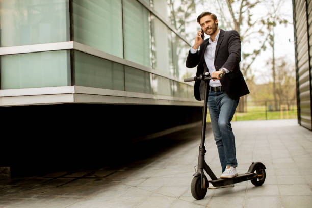 istock Young businessman using mobile phone  on electric scooter 1318625089