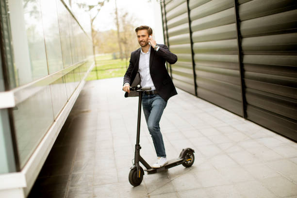 istock Young businessman using mobile phone  on electric scooter 1318625153