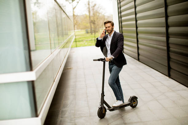 istock Young businessman using mobile phone on electric scooter 1318625170