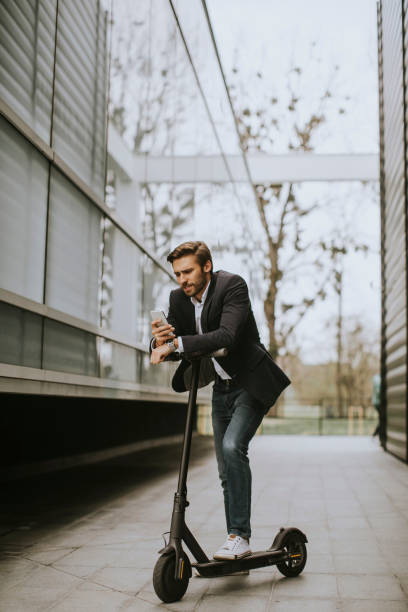 istock Young businessman using mobile phone  on electric scooter 1318625172