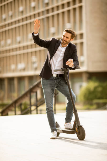 istock Young businessman using mobile phone on electric scooter 1318625174