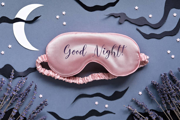 istock Sleep mask with lavender on dark grey background with black clouds, Moon and stars. Text Good night on the mask. Quality of sleep, aromatherapy, scented herbal remedies. Creative top view 1318625634