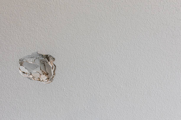 A hole in the wall of a hallways caused by a fist punching through the wall A hole in the wall of a hallways caused by a fist punching through the wall to create a large hole that needs repair. hole stock pictures, royalty-free photos & images