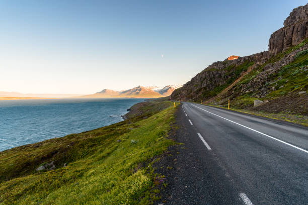istock Empty scenic coast road under clear sky lit by midnight sun. Northern Iceland. 1318627731