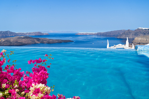 clear pool water and view of Santorini caldera with flowers, Greece