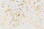 Gold confetti sparkles on white background, golden foil, festive backdrop.