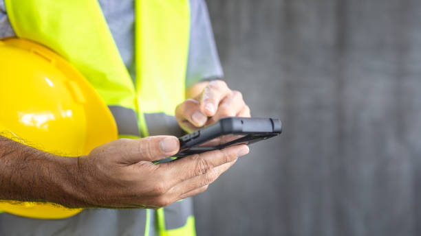 Close up Construction worker hands Touch screen smartphone stock photo