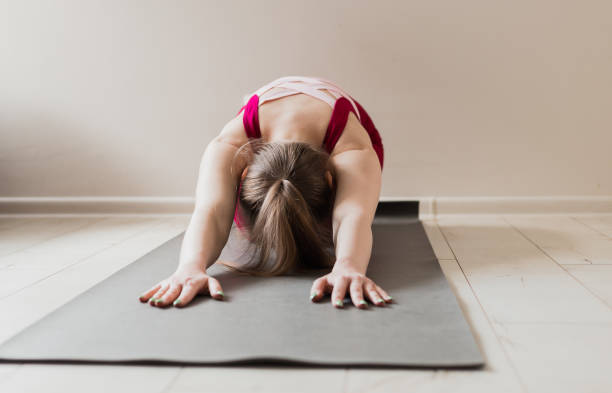 istock Young woman practicing yoga, sitting in Seated forward bend exercise, paschimottanasana pose, working out, wearing pink sportswear, close up. Sport and healthy active lifestyle concept. 1318640739