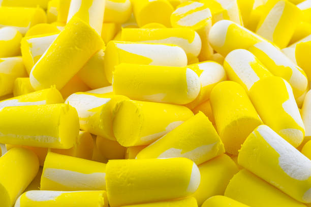 ノイズ保護のための黄色と白の複数の耳栓のマクロショットで作られた背景。 - decibels ストックフォトと画像