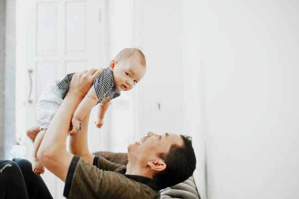 istock happy parent lifting baby boys while sitting on sofa at home 1318642774