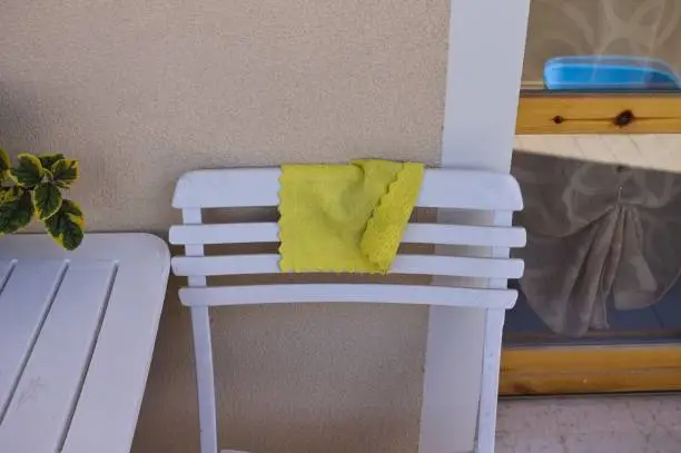 Photo of A yellow rag leaning against a white chair on the balcony (Pesaro, Italy, Europe)