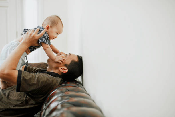 istock happy parent lifting baby boys while sitting on sofa at home 1318642935