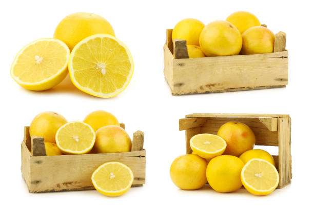 yellow grapefruits and a cut one and some in a wooden crate on a white background