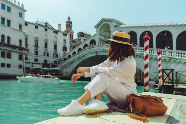 mujer sentada cerca del puente rialto en venecia italia mirando gran canal con góndolas - venice italy rialto bridge italy gondola fotografías e imágenes de stock
