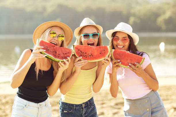 istock Girlfriends at a party eating a watermelon on the beach. 1318651354