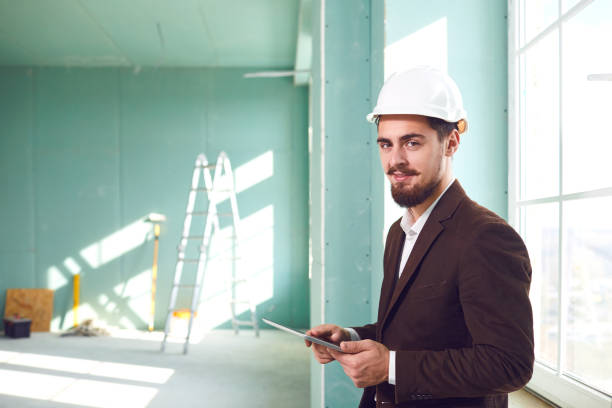 istock Foreman bearded man in a white helmet in a room at a construction site 1318651943