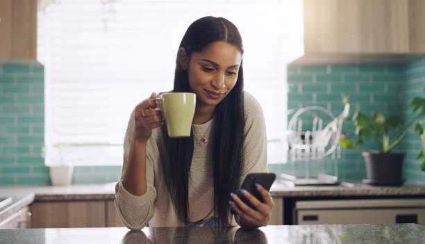 istock Shot of a young woman drinking coffee while using her smartphone at home 1318652893