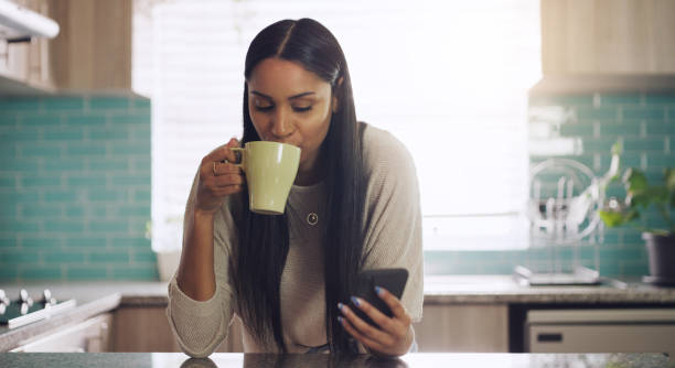 istock Shot of a young woman drinking coffee while using her smartphone at home 1318652906
