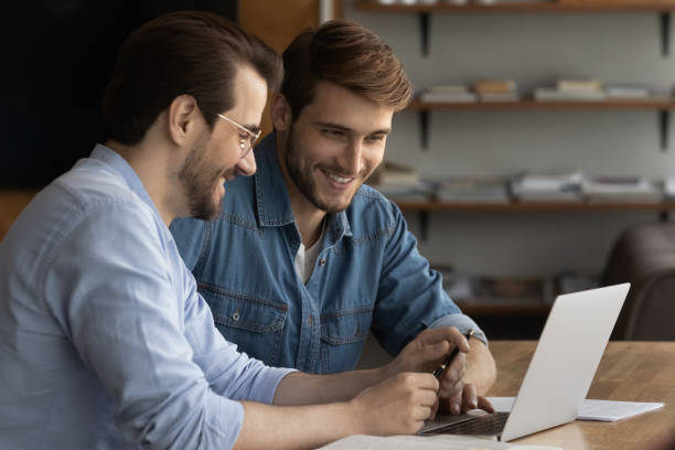 istock Smiling male employees work together on laptop in office 1318654719