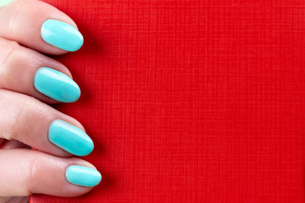 istock Female hand with beautiful manicure - mint blue nails with red leather surface, closeup with copy space 1318655566