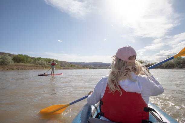 istock POV of woman kayaking down river along with paddle boarder 1318656725