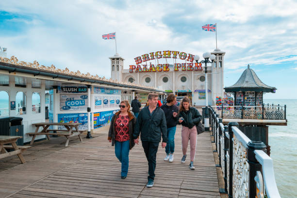Brighton, UK - 17 May, 2021: a group of people walking on the palace pier in Brighton, UK, with blue sky and cloudscape.