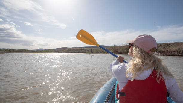 istock POV of woman kayaking down river along with paddle boarder 1318659244