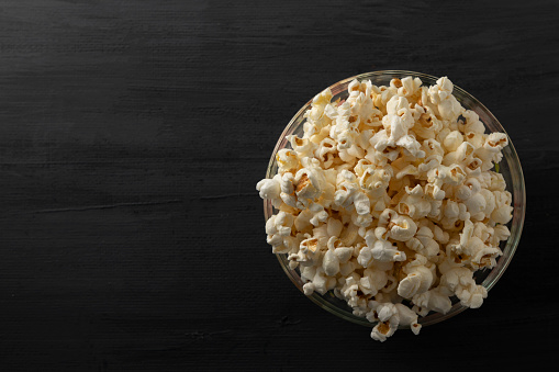 Popcorn in a bowl on a black background with room for text.