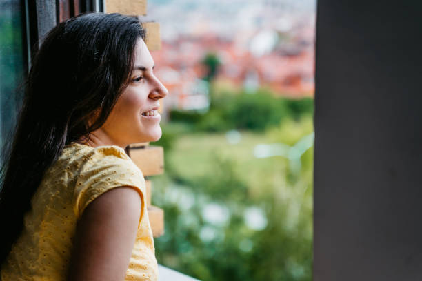 istock Smiling woman looking through window on city 1318664809