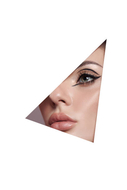 istock Beauty makeup women, eye brows eyelashes and lips in a triangular hole paper white background. Professional beauty makeup, place for text, copy space 1318664898
