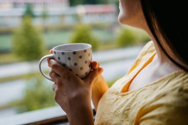 istock Woman drinking coffee at window 1318664937