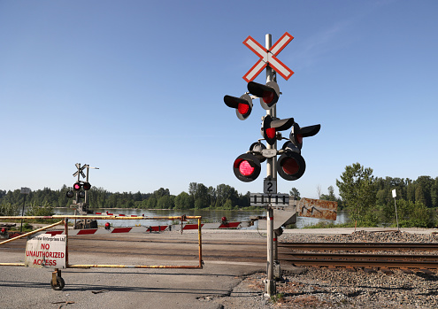 Maple Ridge, Canada - May 16, 2021: An electronic warning device stands at the foot of 225th Street by the Fraser River in Metro Vancouver. The red lights indicate an approaching freight train travelling east through southwestern British Columbia.