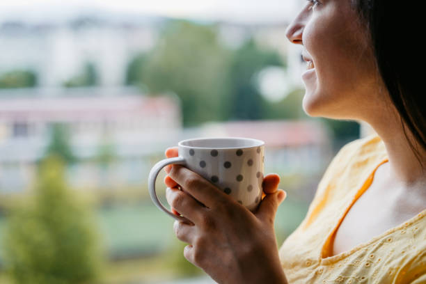 istock Woman drinking coffee at window 1318665012