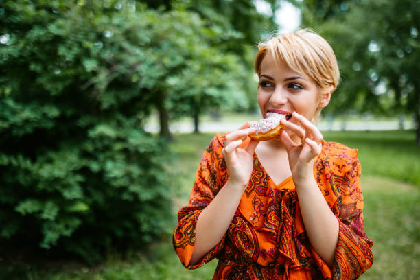 istock Woman eating donut in park 1318666105