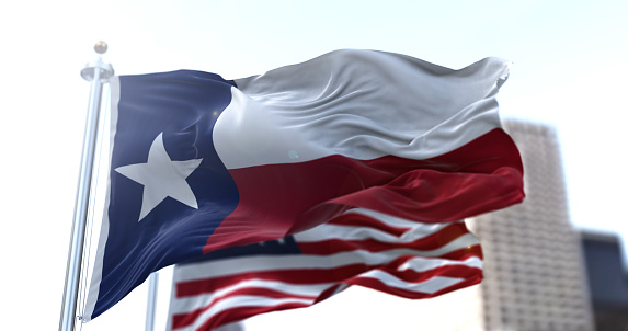 The Texas state flag flapping in the wind with the American national flag blurred in the background. Democracy and independence. American South Central state.