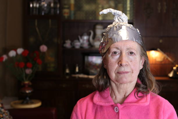 Distrustful senior woman wearing weird tinfoil hat