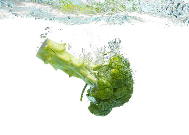 istock Green broccoli falling in water with splash on white with air bubbles. 1318670656