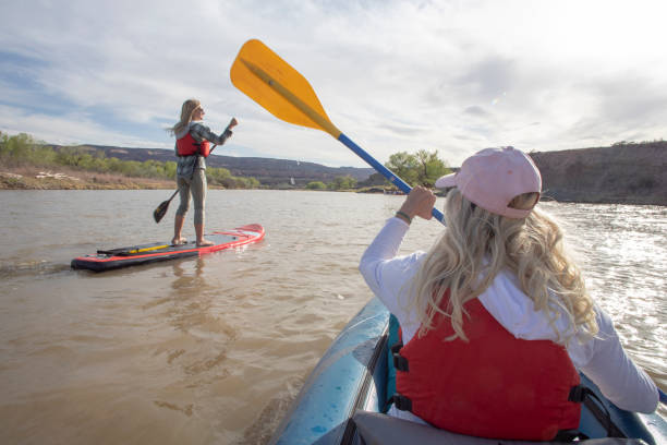 istock POV of woman kayaking down river along with paddle boarder 1318671492