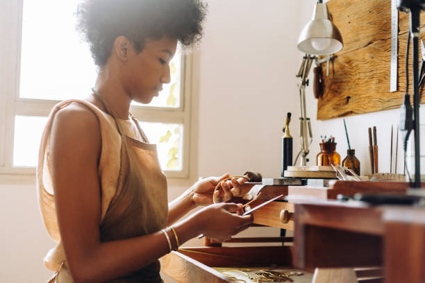 Woman with jewelry and tool in her hands in workshop Woman in a workshop with jewelry and tool in her hands for giving finishing look. Young artist working on accessories in her studio. jewelry craftsperson craft jeweller stock pictures, royalty-free photos & images