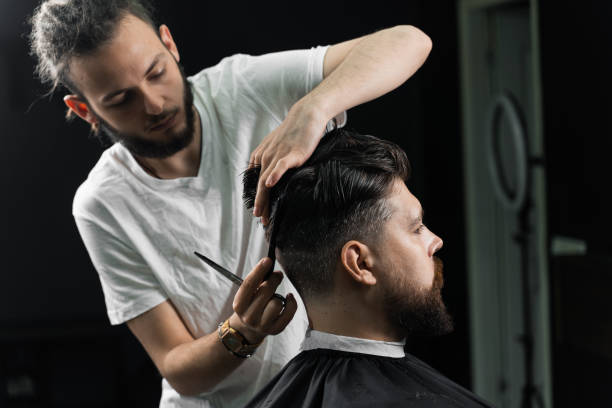 Low fade machine haircut for handsome bearded man in barbershop. Barber with dread locks making hairstyle with a smooth transition. Low fade machine haircut for handsome bearded man in barbershop. Barber with dread locks making hairstyle with a smooth transition fade in stock pictures, royalty-free photos & images