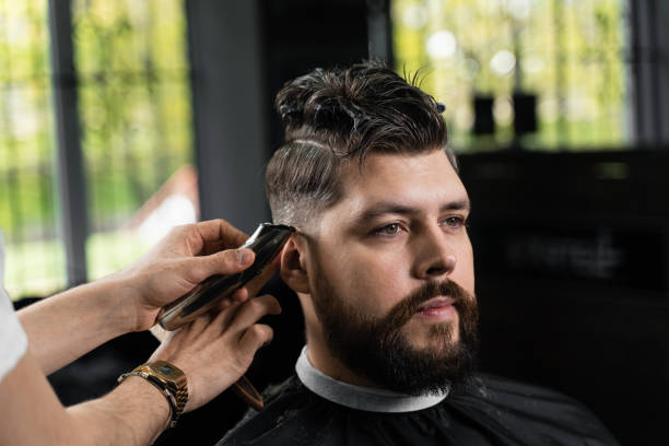 Low fade machine haircut for handsome bearded man in barbershop. Hair cut with a smooth transition. Low fade machine haircut for handsome bearded man in barbershop. Hair cut with a smooth transition fade in stock pictures, royalty-free photos & images