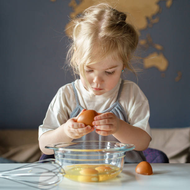 istock Cute little girl breaking eggs into bowl while cooking with mom 1318675399