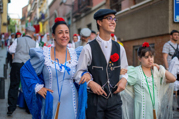 Castizos procession of San Cayetano in Madrid On August 7, 2018, in the neighborhoods of Lavapiés and La Latina Madrid, Spain. the Madrid festivities began with the popular celebration of San Cayetano. 
It is a festivity celebrated in the streets near the parish church of San Cayetano (Madrid) in honor of San Cayetano de Thiene that takes over the streets until August 9, full of activities for citizens of all ages,
He goes out in procession through the streets that border El Rastro, accompanied in his procession by thousands of devotees, and faithful
On the days around the celebration, the streets are adorned with paper garlands and the balconies with Manila shawls. The procession is headed for an associations of catizos ( Madrileños pure blood)  who that day wear their best clothes to accompany the Saint.  It is usually celebrated today with typical costume competitions (goyescos, manolos, chisperos) as we can see in this picture. fete stock pictures, royalty-free photos & images