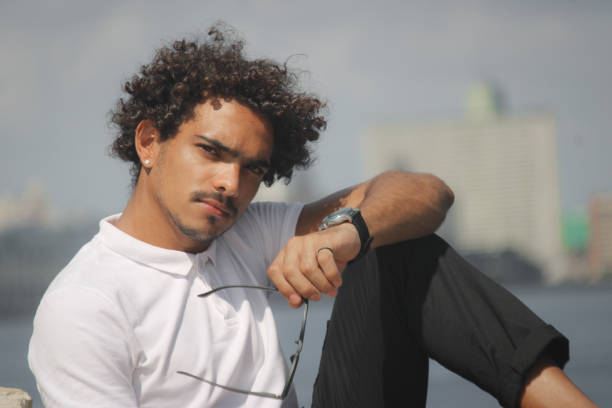 A young man in a white pullover enjoys on the coast in a gray pullover. Young man is happy enjoying nature.